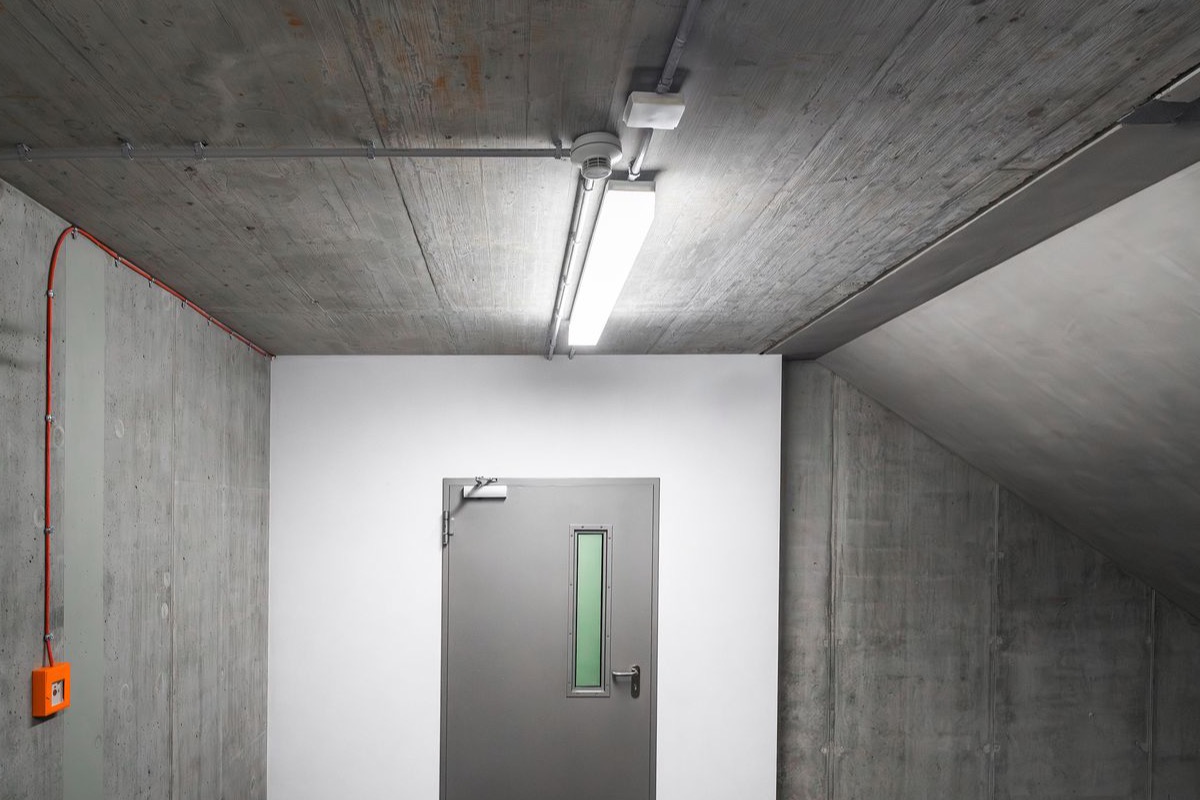 Below-grade concrete stairwell interior with raw board-marked walls and a fire door
